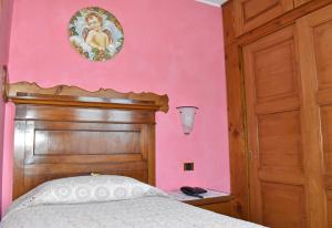 a bedroom with pink walls and a bed with a wooden headboard at Albergo Ristorante Conca Azzurra in Colico
