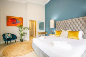Hout & About Guest House في هوت باي: غرفة نوم بسرير ابيض كبير وجدار ازرق