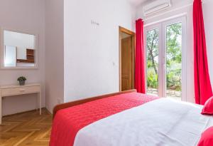 a bedroom with a bed with red curtains and a window at Apartments Jure in Makarska