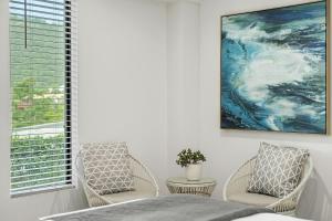 a bedroom with two chairs and a painting on the wall at Airlie Guest House in Airlie Beach