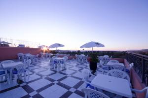 un patio con mesas blancas y sillas en la azotea en Hotel INOU, en Agadir