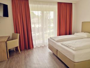 Schlafzimmer mit einem Bett, einem Schreibtisch und einem Fenster in der Unterkunft Hotel Auszeit in Sankt Kanzian am Klopeiner See
