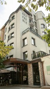 a tall white building with a cafe in front of it at Reverence Boutique Hotel in Varna City