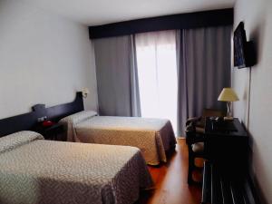 a hotel room with two beds and a window at Hotel Lisboa in Badajoz