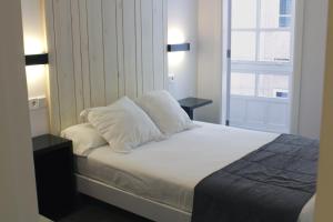 a white bed sitting in a bedroom next to a window at Hotel Lois in A Coruña