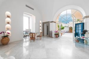 um amplo quarto branco com uma mesa e cadeiras em Villa Magia em Positano