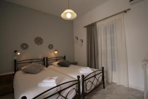 a bedroom with two beds with white sheets and a window at Pension Sofia in Parikia