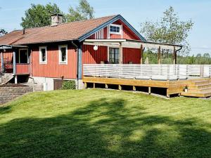 un granero rojo con una gran terraza delante en Holiday Home Svedhagen en Edsbruk