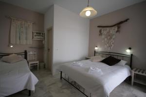 a bedroom with two beds with white sheets at Pension Sofia in Parikia