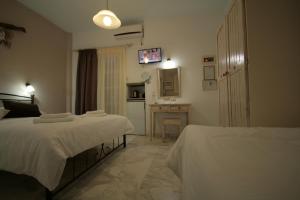 a bedroom with two beds and a desk in it at Pension Sofia in Parikia