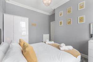 a white bedroom with two beds and a chandelier at No 46 - by StayDunfermline in Dunfermline