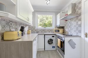 een witte keuken met een wasmachine en een raam bij No 46 - by StayDunfermline in Dunfermline