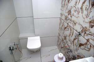 a white bathroom with a toilet and a shower at Hotel Shobhna Palace in Ahmedabad