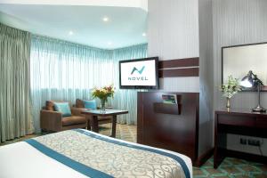 a hotel room with a bed and a living room at Novel Hotel City Center in Abu Dhabi