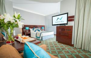a hotel room with a bed and a television at Novel Hotel City Center in Abu Dhabi