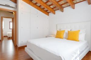 a white bedroom with a white bed with yellow pillows at Apartamentos Sherry Center in Jerez de la Frontera