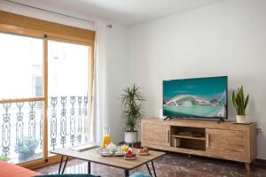 sala de estar con TV de pantalla plana en un centro de entretenimiento de madera en Singularstays Ruzafa Terrace, en Valencia