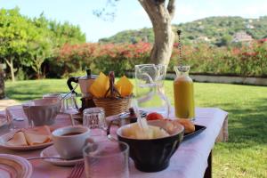 einen Tisch mit Teller mit Lebensmitteln und einer Flasche Saft in der Unterkunft B&B Kapì Country in Alghero