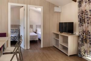 a small room with a television and a bedroom at Camping Giralda in Huelva