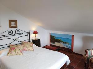 a bedroom with a white bed and a painting on the wall at Hotel Rural El Pagadín in Ribadesella
