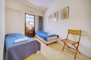 um quarto com 2 camas, uma cadeira e uma janela em Apartments Louis Blanc/Forville em Cannes