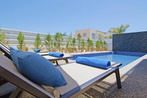 two benches with blue pillows sitting next to a swimming pool at Villa Melody in Protaras