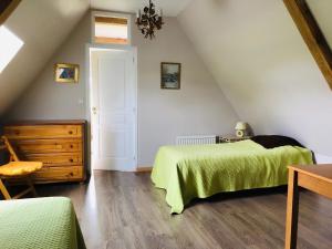 un dormitorio en el ático con 2 camas y una silla en LE PETIT MARAIS en Clais
