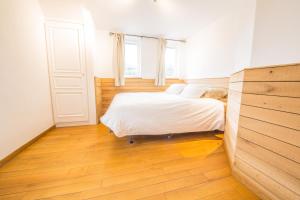 1 dormitorio con 1 cama con sábanas blancas y suelo de madera en La Maison du Verger, en Durbuy