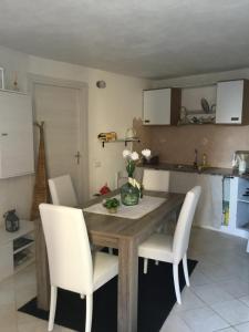 een keuken met een houten tafel en witte stoelen bij Dommu Asile in Baunei