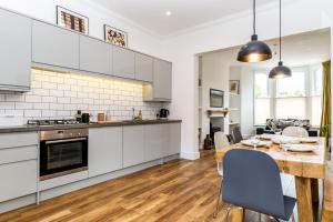 a kitchen and dining room with white cabinets and a wooden table at City Apartments - Priory Street in York
