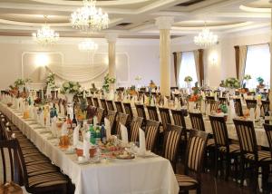 a long table in a room with chairs and chandeliers at Dworek Saski in Radom