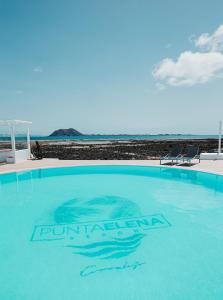 een groot zwembad met de oceaan op de achtergrond bij Apartamentos Punta Elena Beach in Corralejo