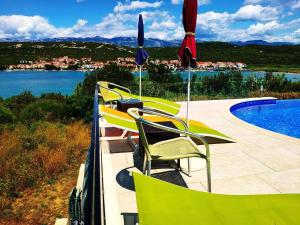 un grupo de sillas y sombrillas junto a una piscina en Villa Vila, en Novalja