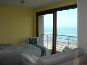 a bedroom with a bed and a balcony with a television at Studio apartment 'De Strandwandeling' with frontal sea view near Ostend in Ostend