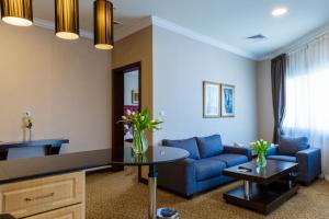 a living room with a blue couch and a table at Kingsgate Hotel Doha by Millennium Hotels in Doha