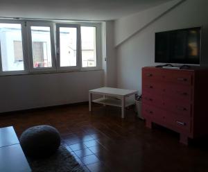 sala de estar con TV, vestidor y ventanas en Mansarda a 50 metri dal mare, en Porto SantʼElpidio