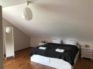 a bedroom with a white bed with a black blanket at Dom Sówka in Radzyń