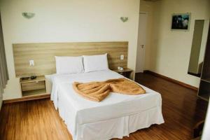 a bedroom with a white bed with a blanket on it at Dalle Hotel in Bagé