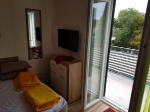 a living room with a television and a balcony with a television at studio apartman Lanterna in Tribunj
