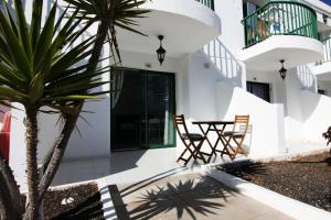 een patio met een tafel en stoelen en een palmboom bij La Perla de S.Valentin in Corralejo