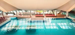 a large swimming pool with red chairs in a building at Hotel Germania Gastein - ganzjährig inklusive Alpentherme Gastein in Bad Hofgastein