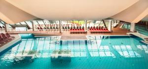 a large swimming pool with red chairs in a building at Hotel Germania Gastein - ganzjährig inklusive Alpentherme Gastein & Sommersaison inklusive Gasteiner Bergbahnen in Bad Hofgastein