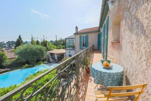 a balcony with a table and chairs and a swimming pool at Vencianne in Vence