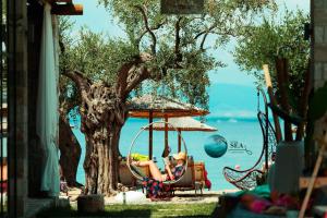 a woman sitting in a chair under a tree at By the sea luxury suites in Limenas