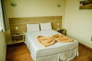 a bedroom with a bed with a blanket on it at Dalle Hotel in Bagé