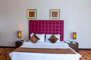 a bedroom with a large bed with a red headboard at Kingsgate Hotel Doha by Millennium Hotels in Doha
