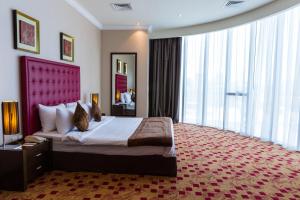 a hotel room with a large bed and large windows at Kingsgate Hotel Doha by Millennium Hotels in Doha