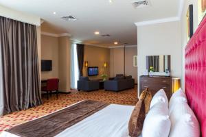 a hotel room with a bed and a living room at Kingsgate Hotel Doha by Millennium Hotels in Doha