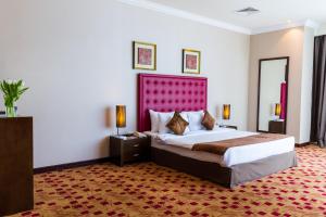 a bedroom with a large bed with a red headboard at Kingsgate Hotel Doha by Millennium Hotels in Doha