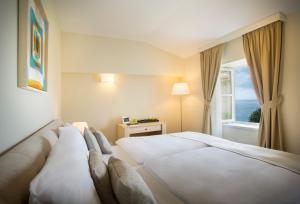 una camera d'albergo con letto e finestra di Apartments Belvedere - Liburnia a Lovran (Laurana)